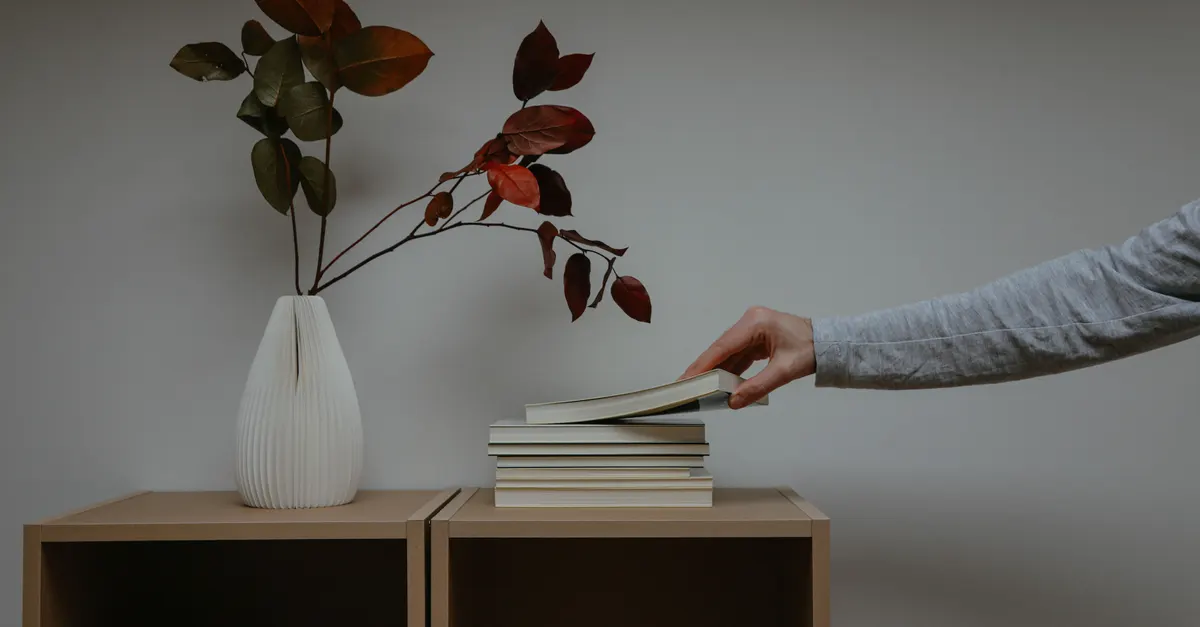 دستی در حال چیدن کتاب روی قفسه‌ای مرتب، نماد سازمان‌دهی کتابخانه اسکریپت